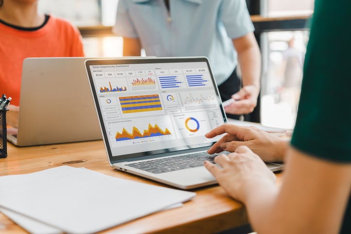 Insurance business professionals reviewing an incentive compensation dashboard on a laptop screen