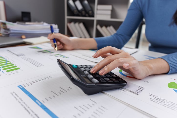 Close-up of a person using a calculator and laptop at a desk, symbolizing manual incentive compensation processes before modern ICM tools.